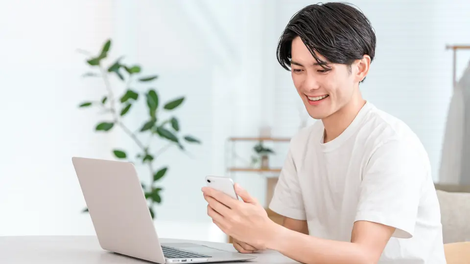 パソコンとスマホを使う男性(投資・副業)