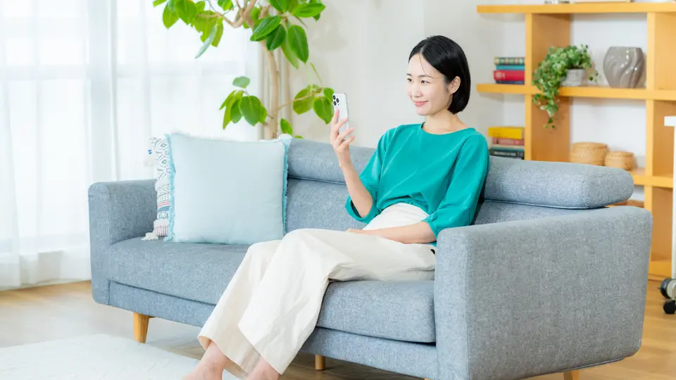 部屋でスマホを操作する女性
