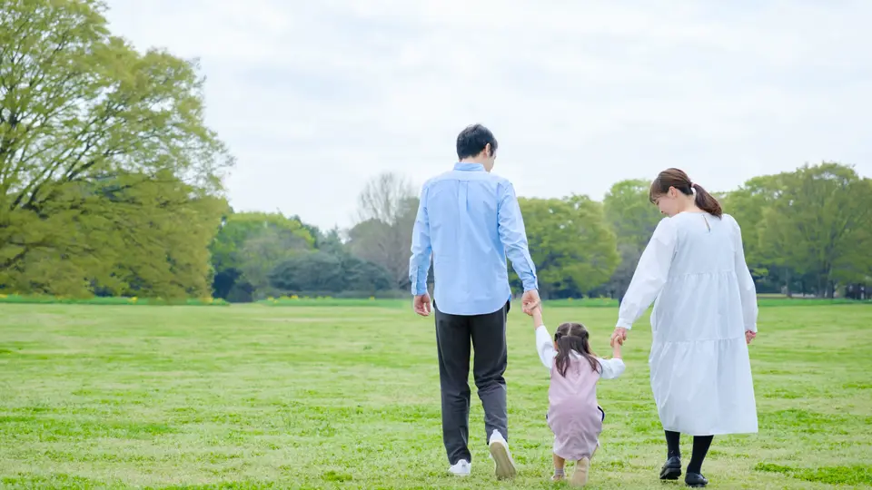 公園で手を繋いで歩く親子の後ろ姿