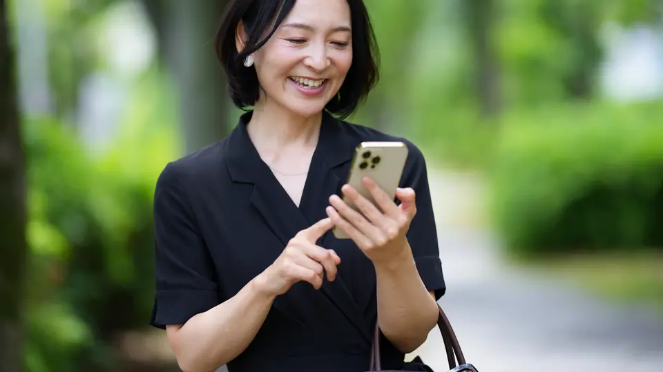 バッグを持ちスマホを見る笑顔の女性