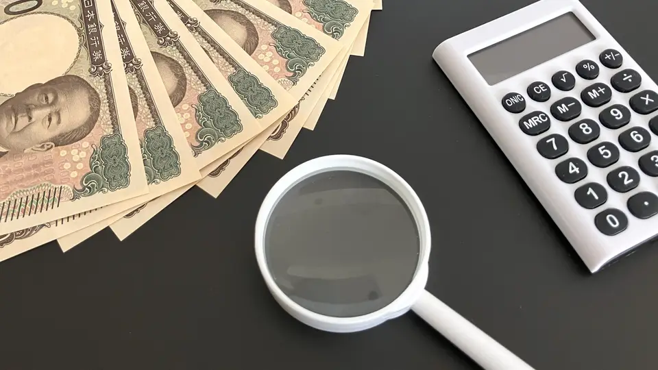 お金と電卓2つとスマホと虫眼鏡