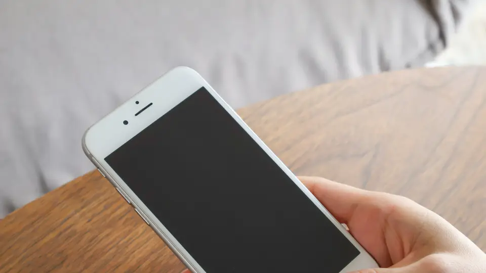 机上でスマホを持つ女性の手元