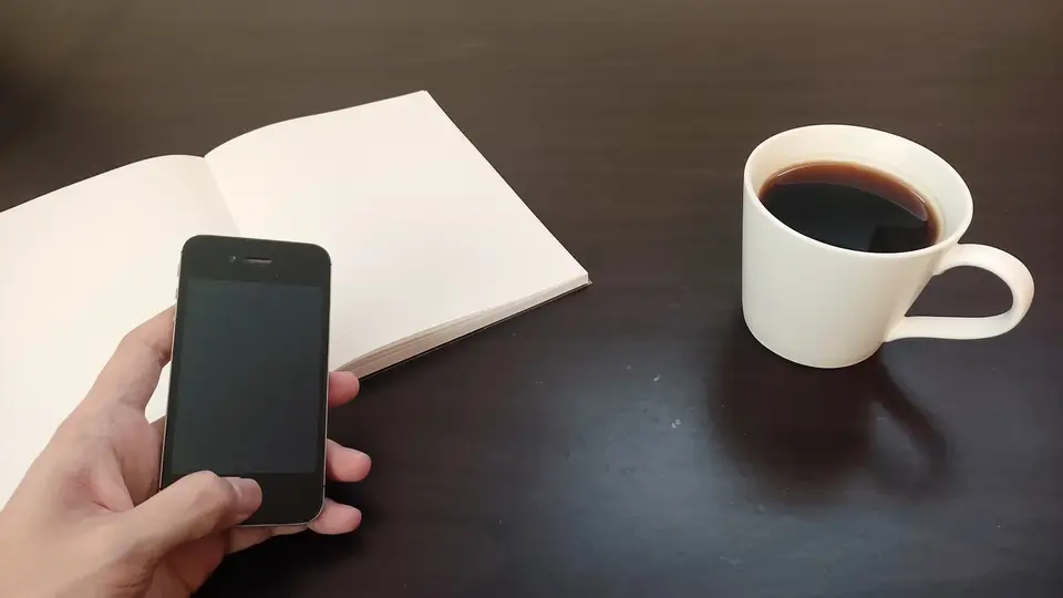 コーヒーとノート、スマホを持つ手