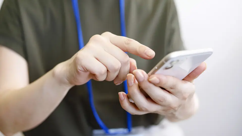 スマホを操作するネームプレートを下げた人