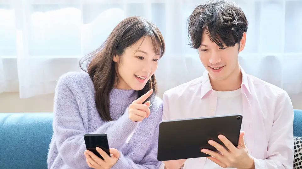 スマホとタブレットの画面を見比べる男女
