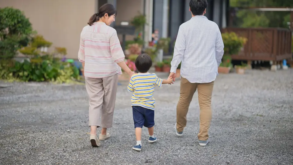 手をつないで歩く家族の後ろ姿