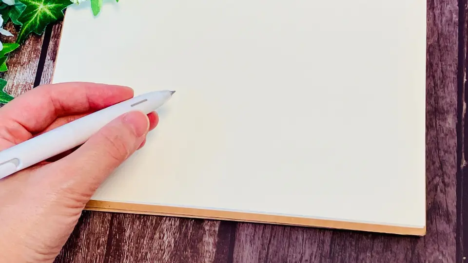 白紙のリングノートに書き込む手元